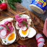 Äggmacka på rågbröd toppad med Kalles Sill, picklad rödlök, rädisor och dill