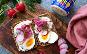 Äggmacka på rågbröd toppad med Kalles Sill, picklad rödlök, rädisor och dill