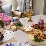Burkar med Abba Citron- och ramslökssill, Abba, Fransk löksill och Abba Skärgårdssill på ett dukat bord med olika tillbehör som räkor, ägg, gräslök och kavring.