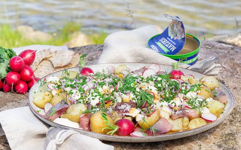 Silltallrik i somrig miljö med Abba matjes, brynt smör, rädisor, gräslök, dill och färskpotatis.